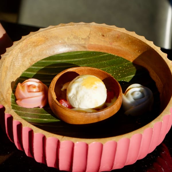 Thai dessert with ice cream, red rubies, and rose-shaped jellies in a wooden bowl.