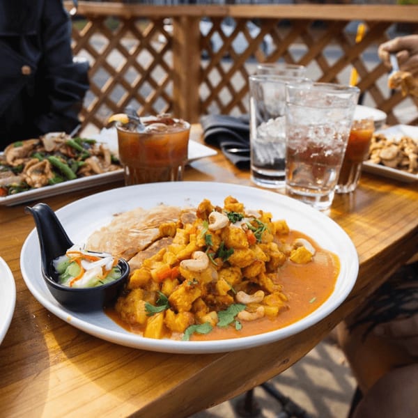 Thai yellow curry with cashews and roti bread, served with a side of pickled vegetables.
